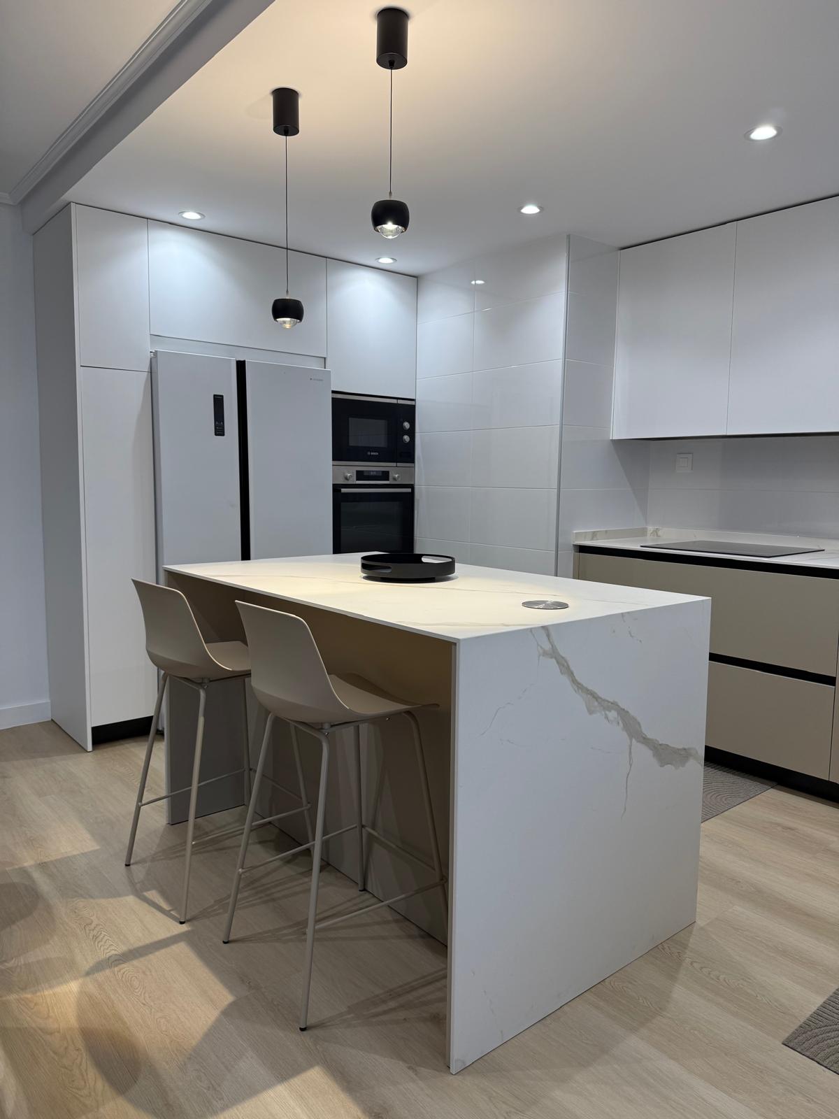 Cocina con columna de electrodomésticos integrada y nevera americana