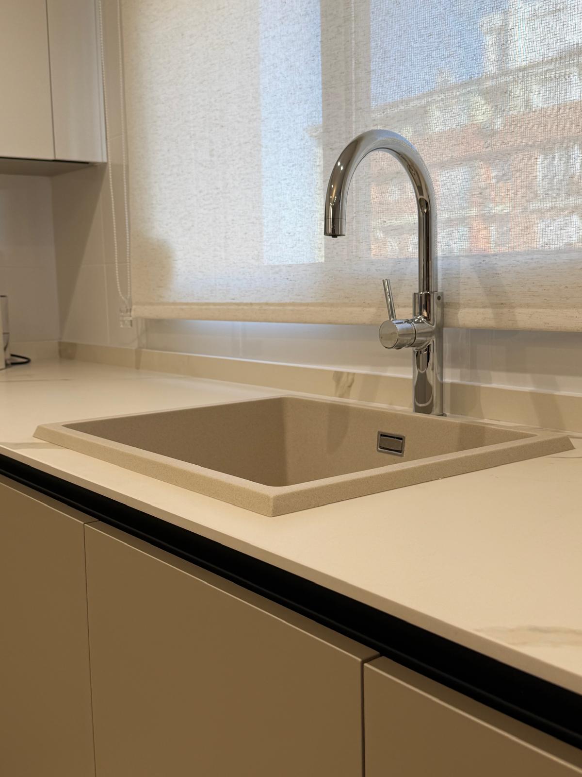 Fregadero sobre encimera con grifería cromada junto a la ventana